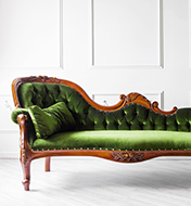 A green couch with a wood frame inside a white room